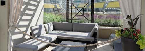 Alternate view of the cabana at AMLI River North with an L shaped couch and a bright potted plant with white curtains