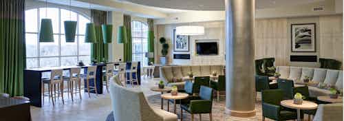 AMLI Evanston lounge with beige couches and leather chairs as well as a barstool seating area with green lighting fixtures