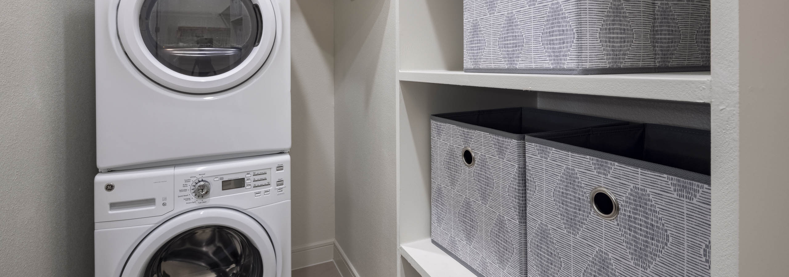 AMLI Lakeline apartment walk-in closet with white stackable full size laundry and washer machines next to storage shelves