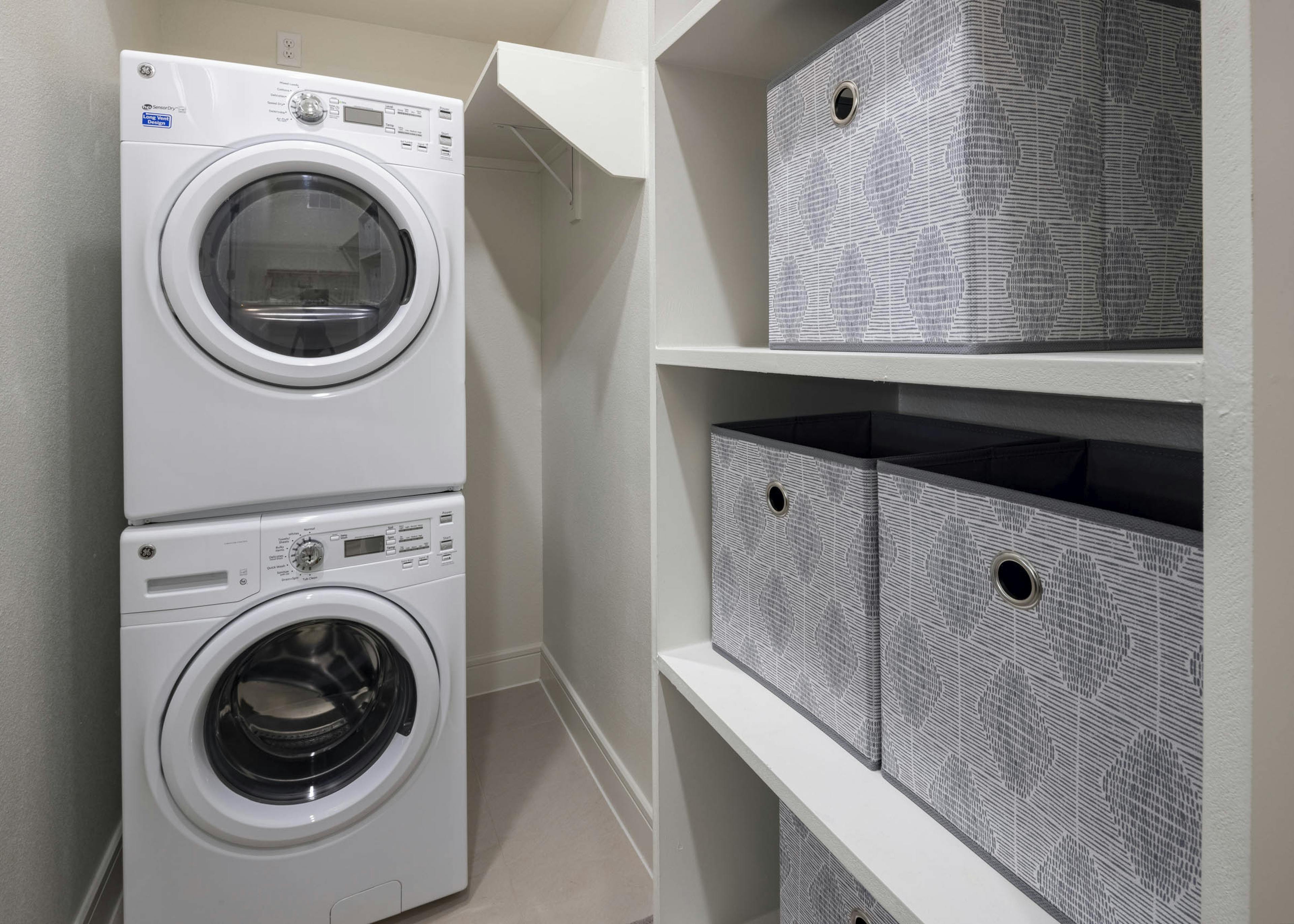 AMLI Lakeline apartment walk-in closet with white stackable full size laundry and washer machines next to storage shelves
