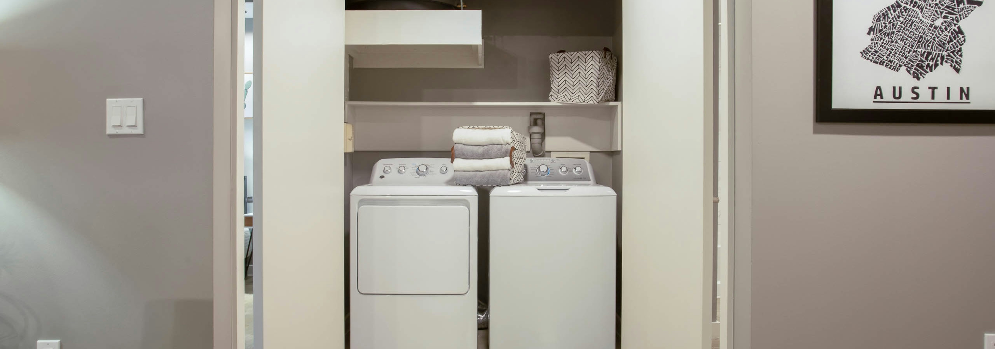 Interior view of in unit laundry machines at AMLI Downtown which are tucked away in a closet with folding doors