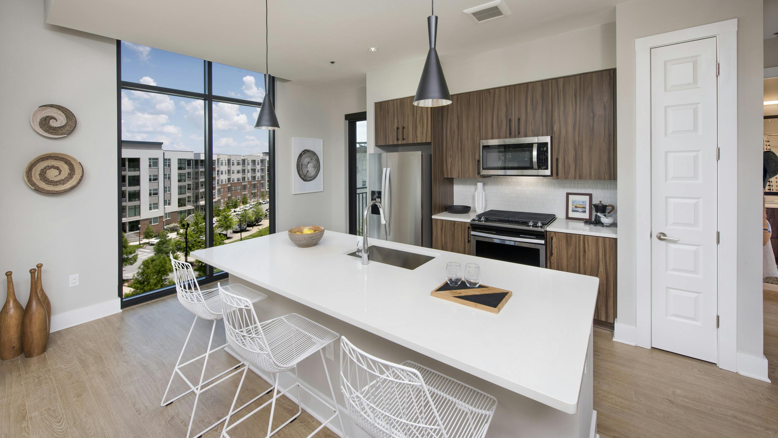AMLI Lenox apartment kitchen with dark brown cabinets and stainless steel appliances and kitchen island and large window