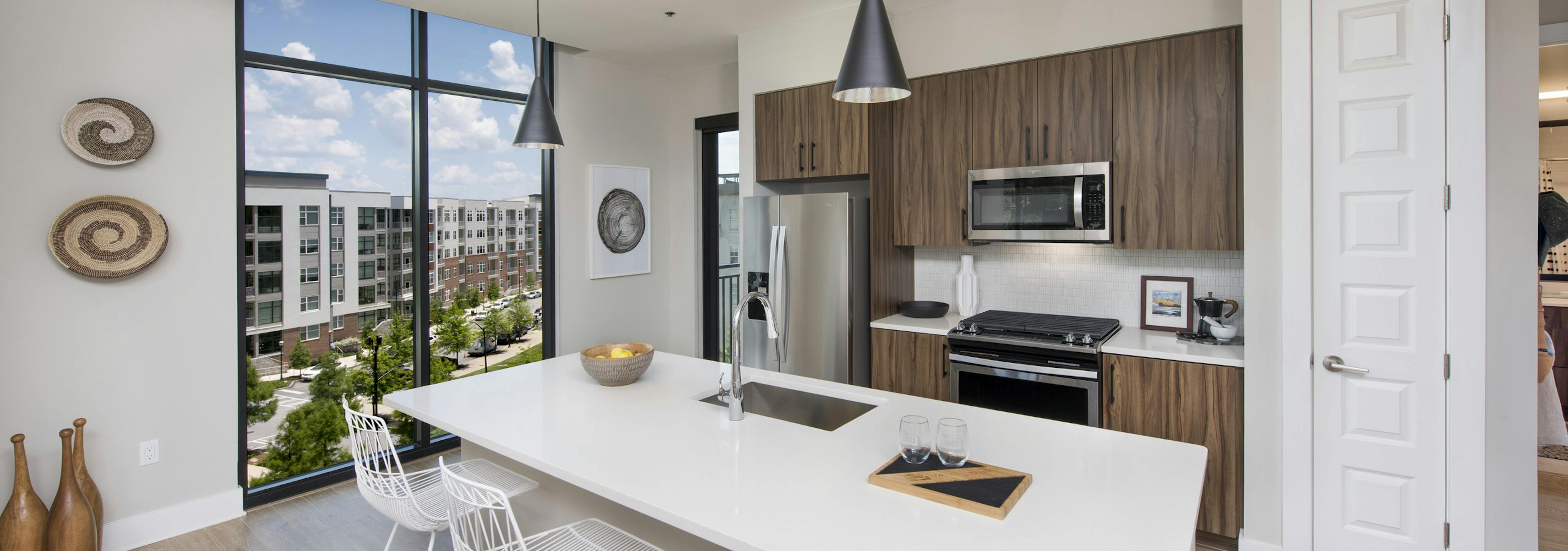 AMLI Lenox apartment kitchen with dark brown cabinets and stainless steel appliances and kitchen island and large window