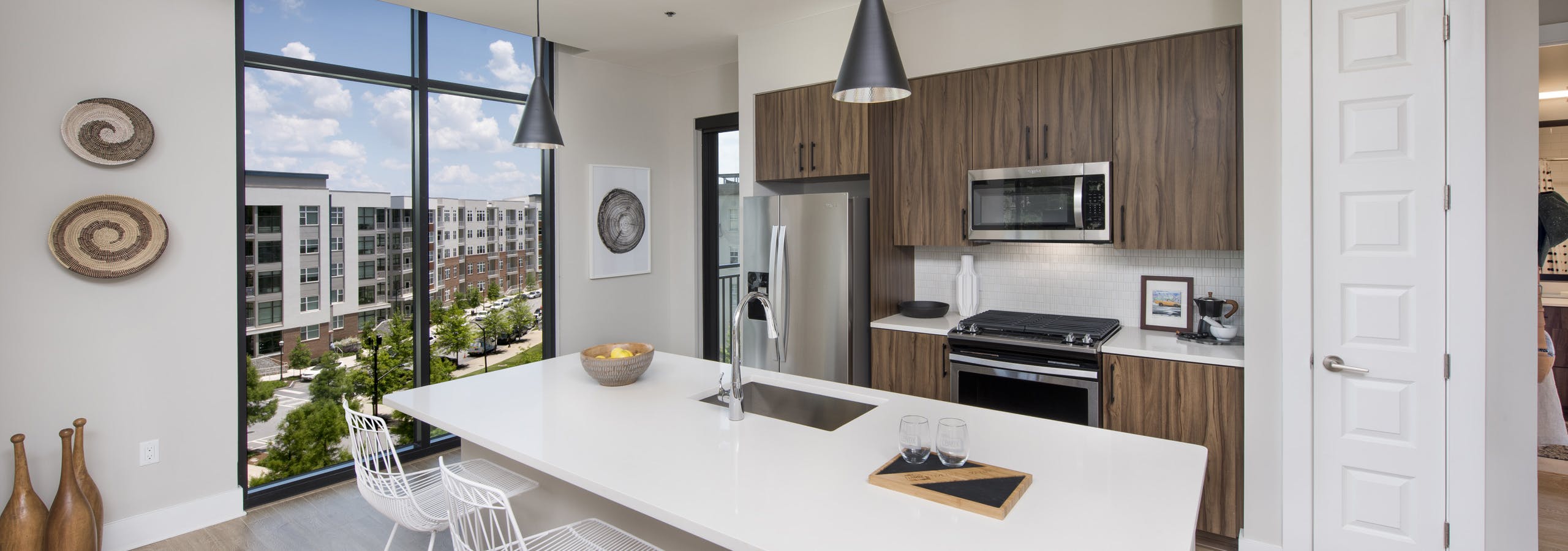 AMLI Lenox apartment kitchen with dark brown cabinets and stainless steel appliances and kitchen island and large window