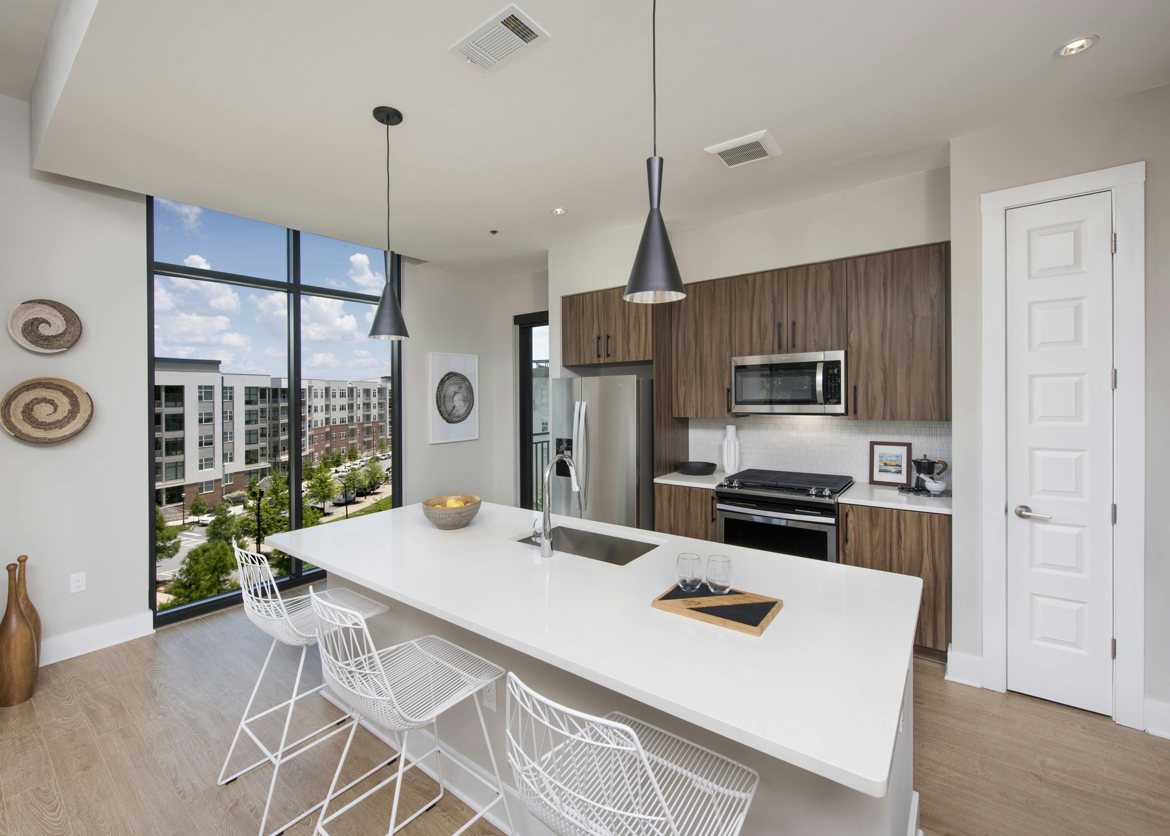 AMLI Lenox apartment kitchen with dark brown cabinets and stainless steel appliances and kitchen island and large window