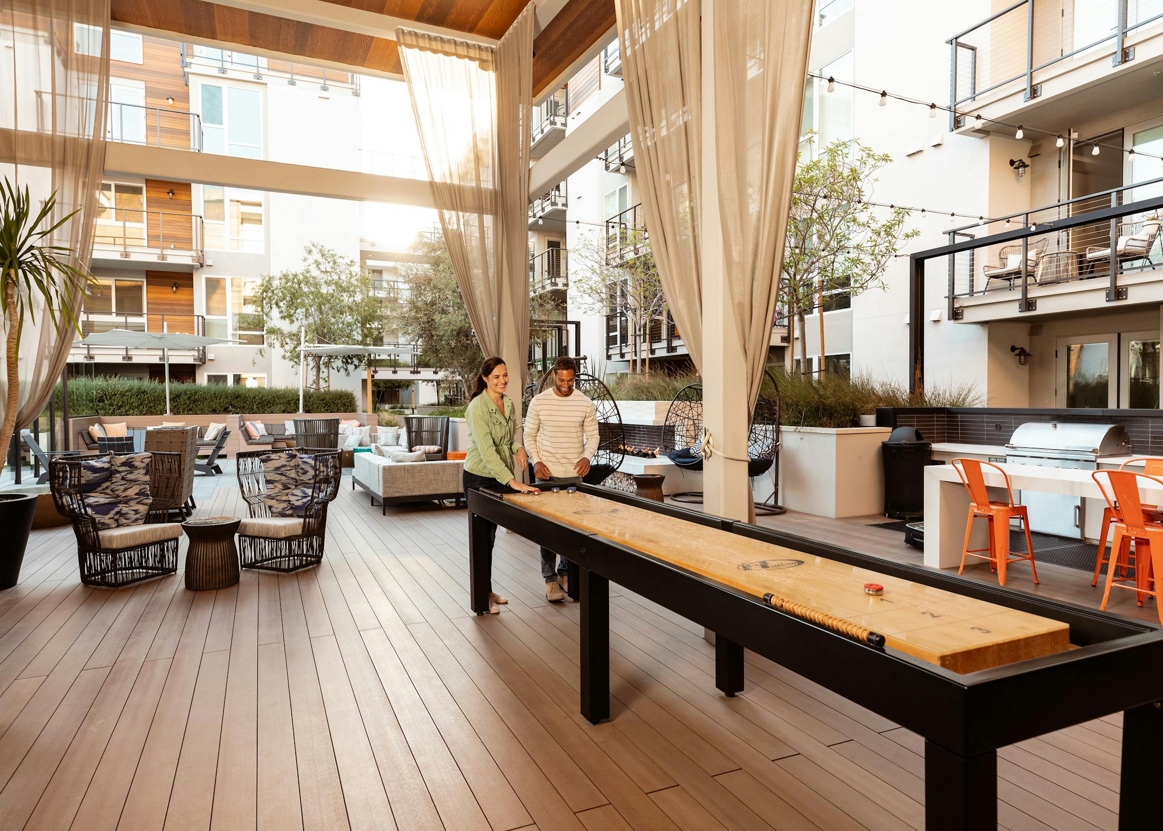 AMLI Marina Del Rey apartment residents playing shuffleboard with luxurious lounge chairs and white modern building exterior