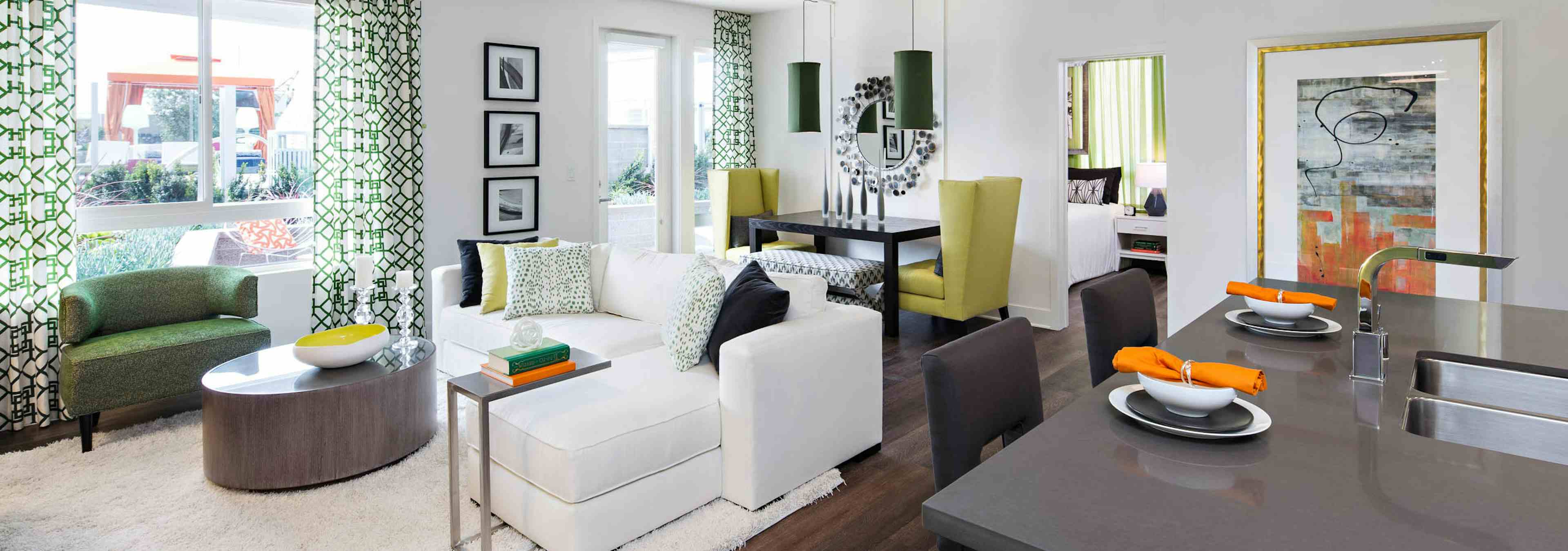 Interior of AMLI Lex on Orange furnished apartment living room with white couch and dining table in front of large windows