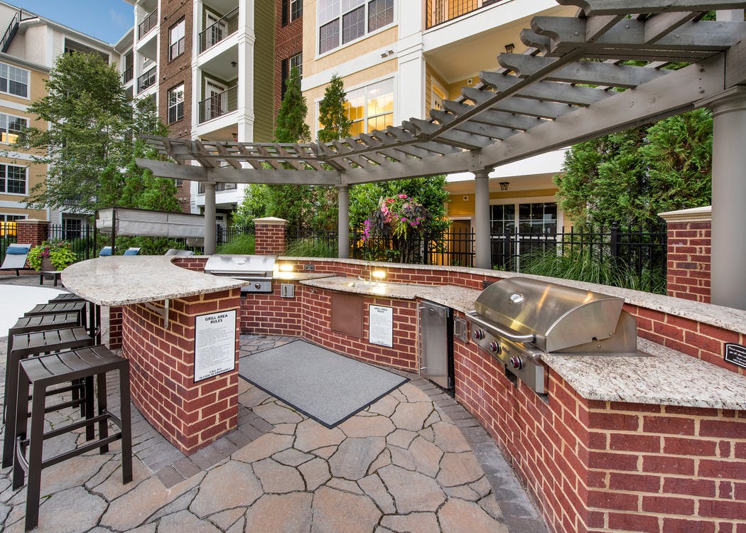 Outdoor kitchen area at AMLI North Point with red brick under white wrap around countertops with a grill and barstools