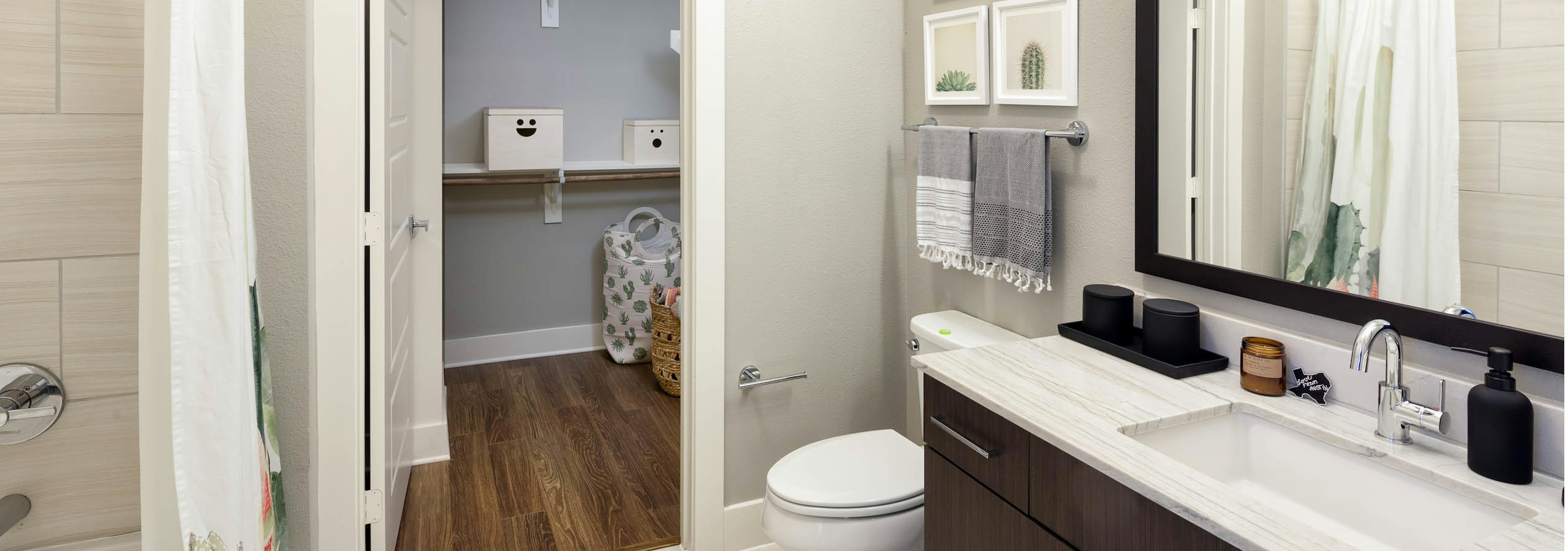 AMLI on Aldrich bathroom featuring dark vanity sink with a white countertop and framed mirror with peek into walk in closet