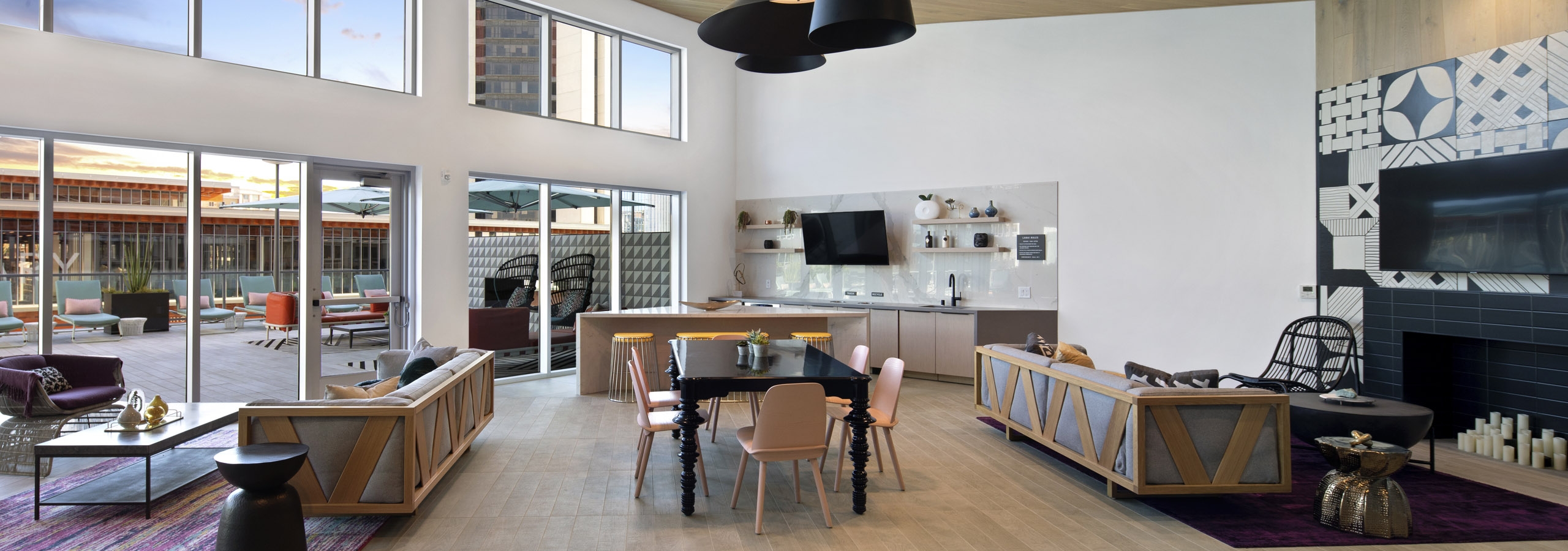 Interior view of clubhouse at AMLI Park Broadway with black table and six pink chairs at center and various seating