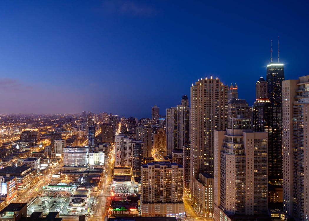 Nightime shot of downtown Chicago with lit skyscrapers and deep blue sky.