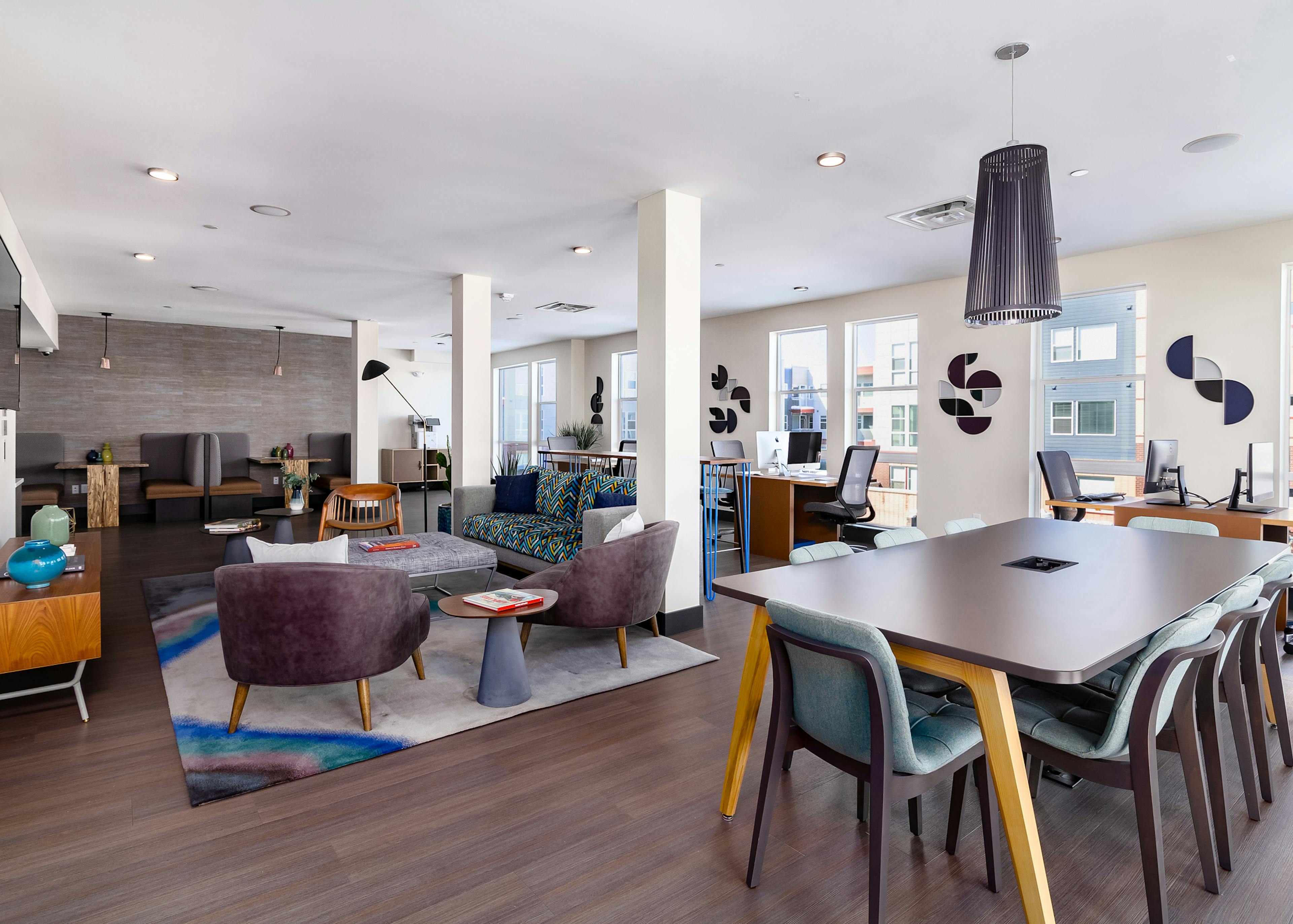Interior of business center with computers, various multi-colored seating and mounted TV at AMLI Littleton Village apartments
