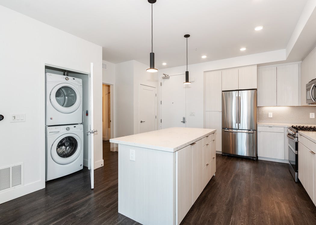 Interior of AMLI Park Broadway apartment kitchen with white cabinetry, stainless steel appliances and full washer and dryer