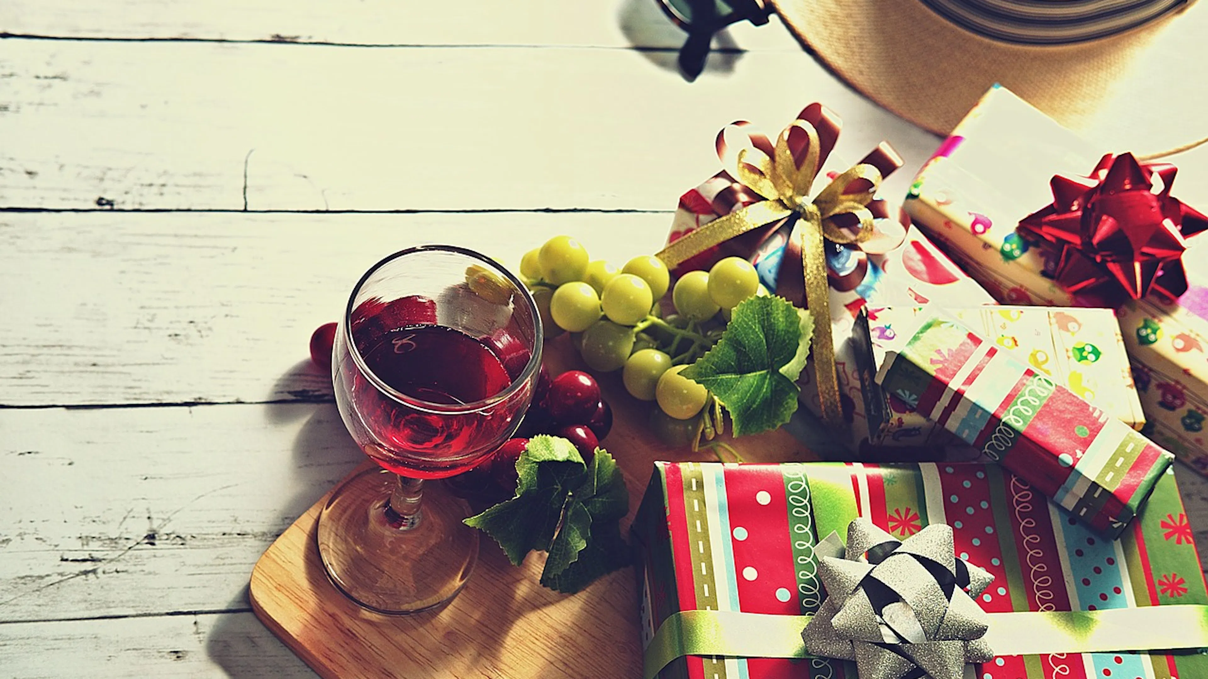 white boards with glass of wine and grapes and small gifts wrapped in red and green