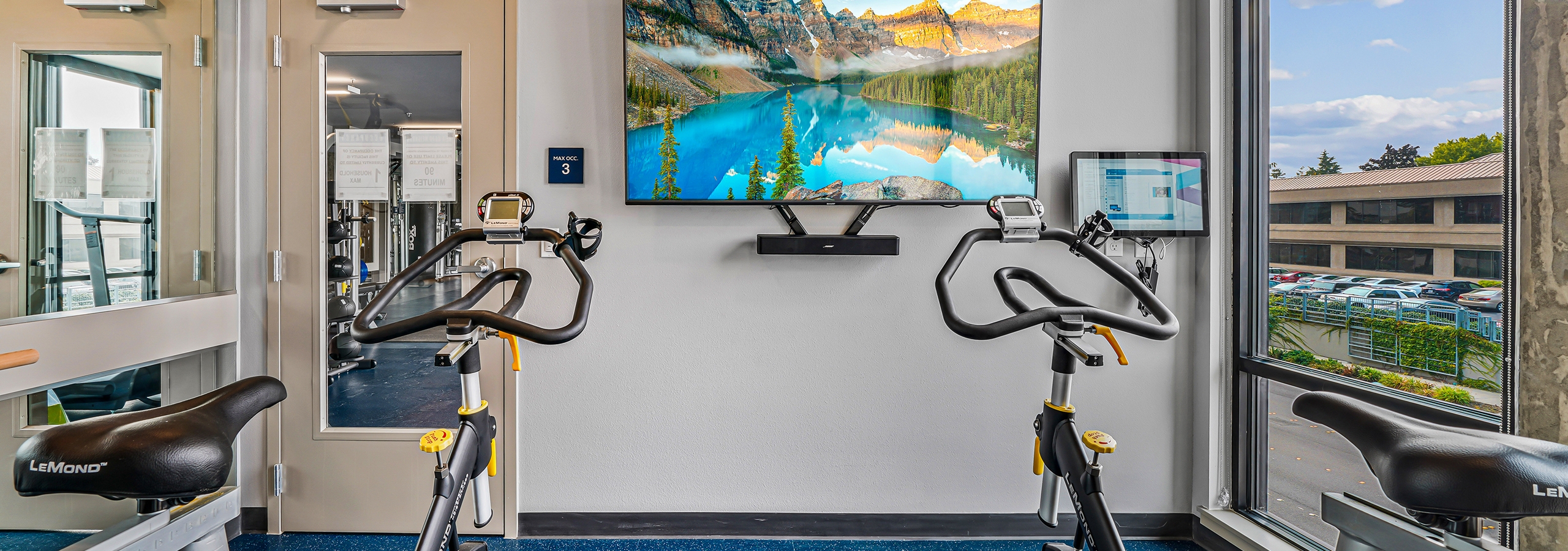 Interior view of spin room at AMLI Spring District apartments with 2 bikes and mounted big screen TV for fitness on demand