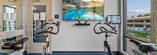 Interior view of spin room at AMLI Spring District apartments with 2 bikes and mounted big screen TV for fitness on demand