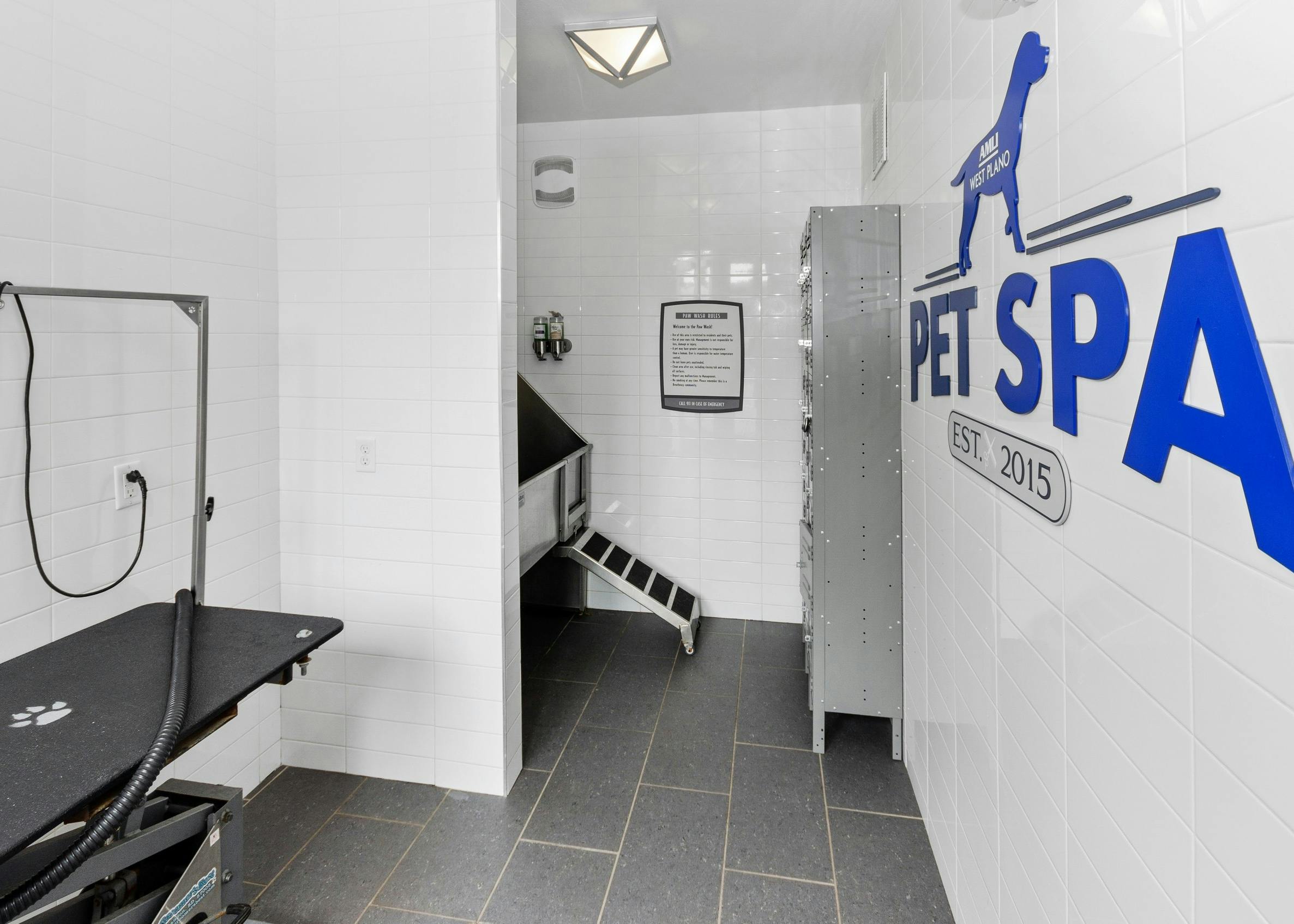 Pet spa at AMLI West Plano including pet washing and drying stations and pet lockers surrounded by white tile walls