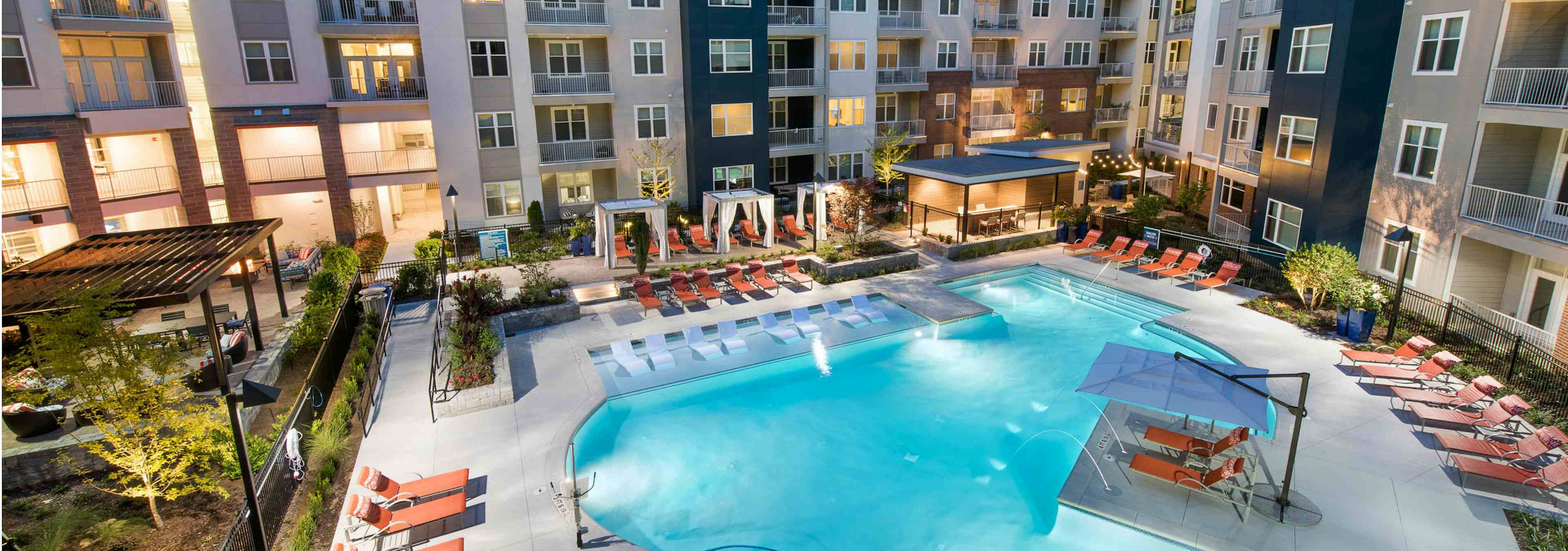 Angle of AMLI Buckhead pool facing the building exterior with surrounding orange lounge chairs on the pavement