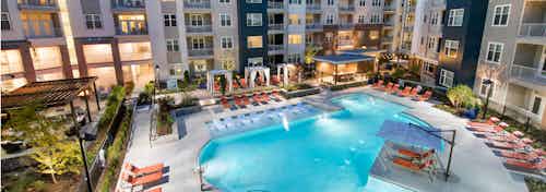 Angle of AMLI Buckhead pool facing the building exterior with surrounding orange lounge chairs on the pavement