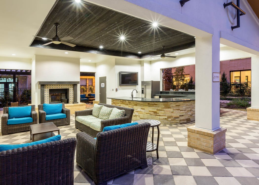 Evening view of AMLI Campion Trail cabana with fireplace and comfortable seating and serving bar with large screen TV