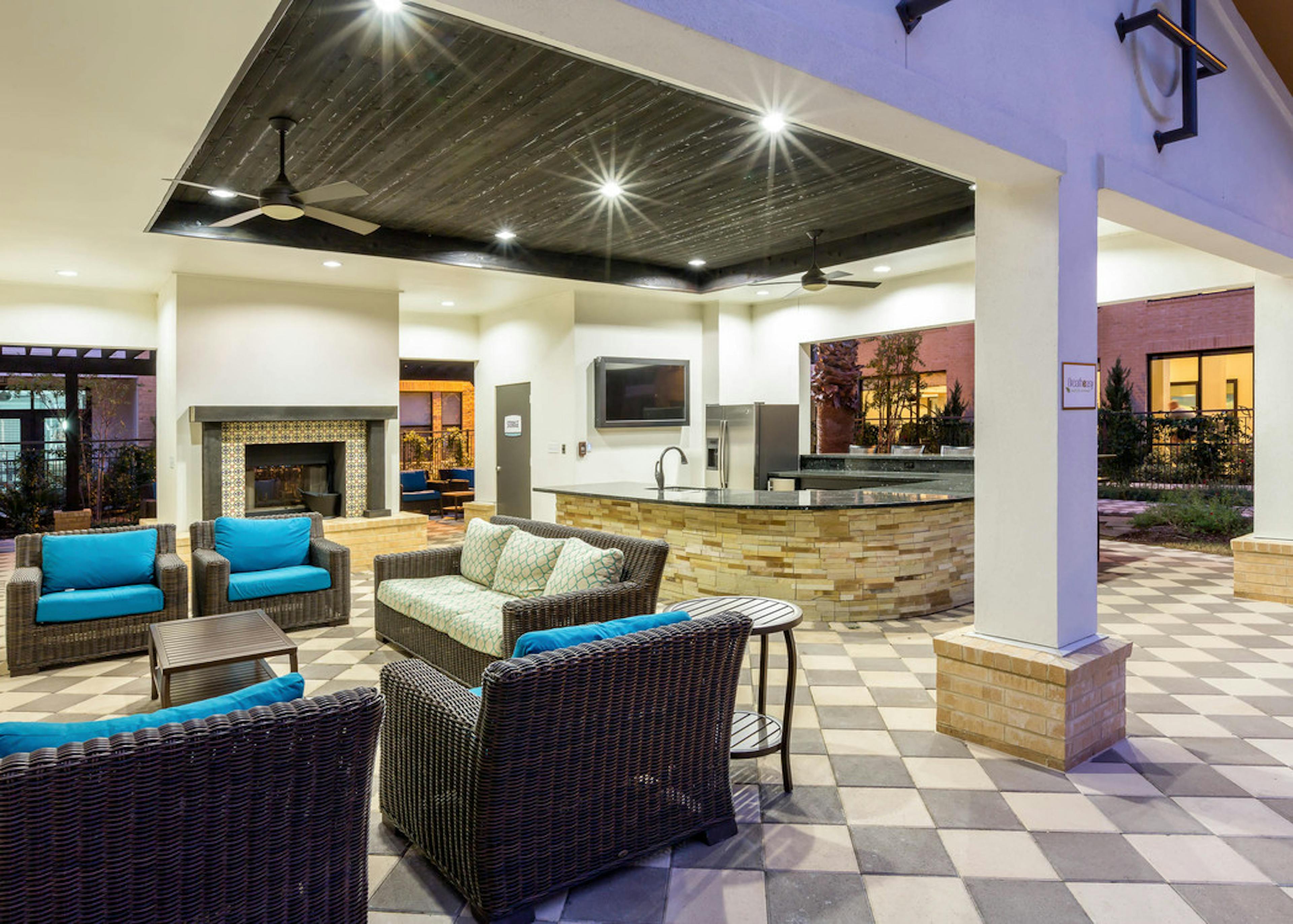 Evening view of AMLI Campion Trail cabana with fireplace and comfortable seating and serving bar with large screen TV