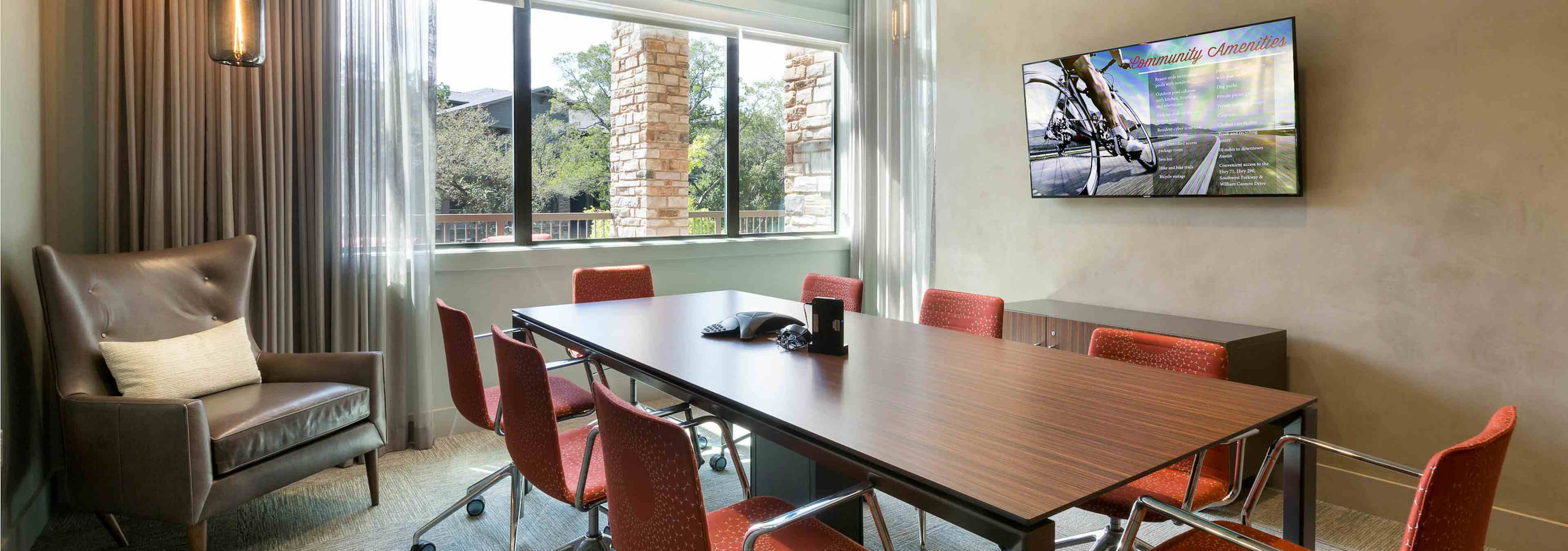 Interior view of AMLI Covered Bridge resident conference room with an eight-person table and a large screen monitor