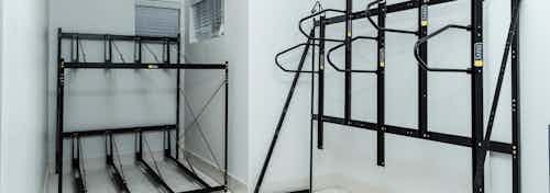 Interior view of the bike storage room at AMLI Arista apartments showcasing black bike racks with white walls and two windows