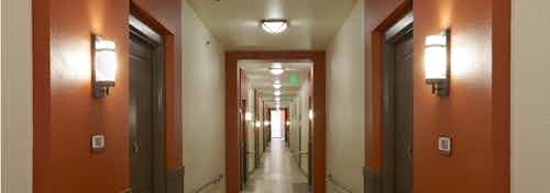 Interior view of hallway at AMLI on Riverside with light walls and modern light fixtures next to each apartment door
