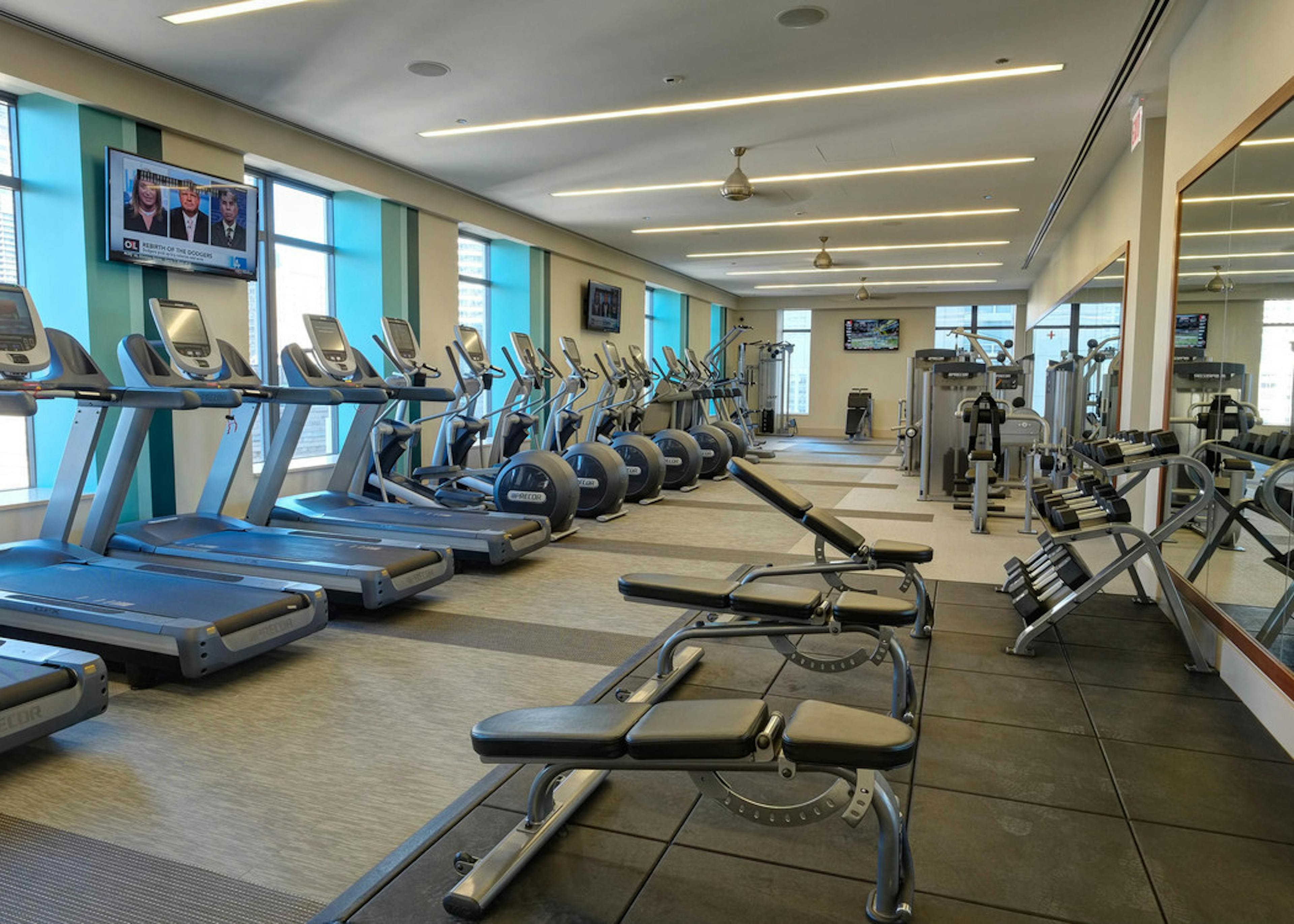 AMLI River North fitness center with treadmills along the wall and an area with shelved dumbbells in front of a mirror