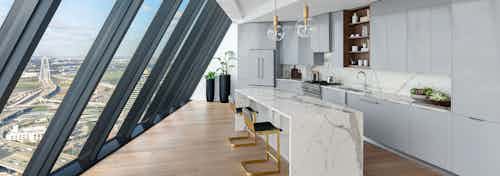 Kitchen with white stone island and gray cabinets and floor to ceiling sloped windows at AMLI Fountain Place apartments
