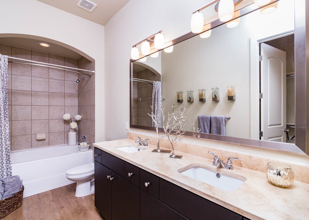 A bathroom at AMLI Ridgegate apartments with a granite counter top with two sinks and a large mirror with view of the shower