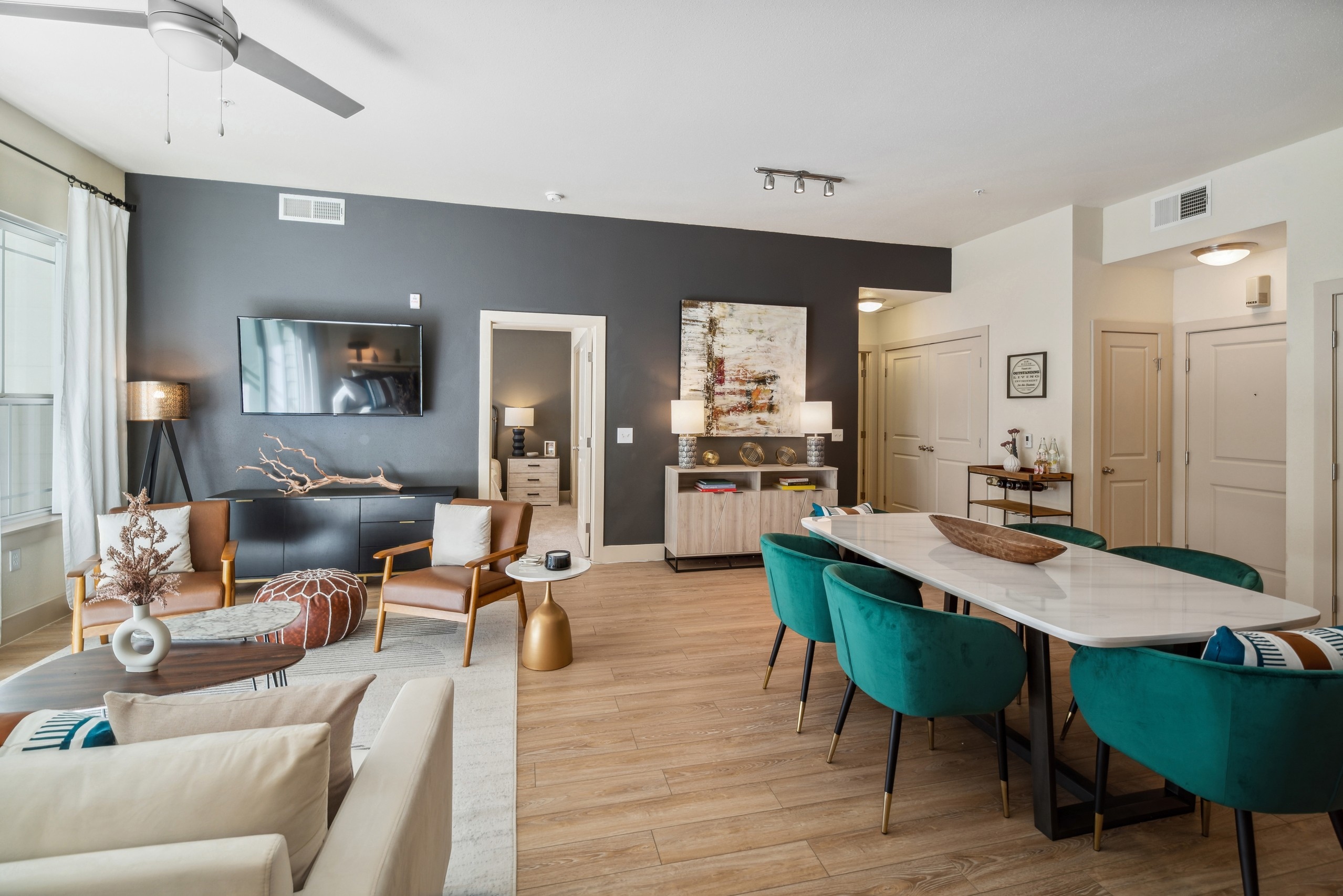 AMLI Park Avenue living and dining room with a white dining table and seating facing large TV set on wood floors