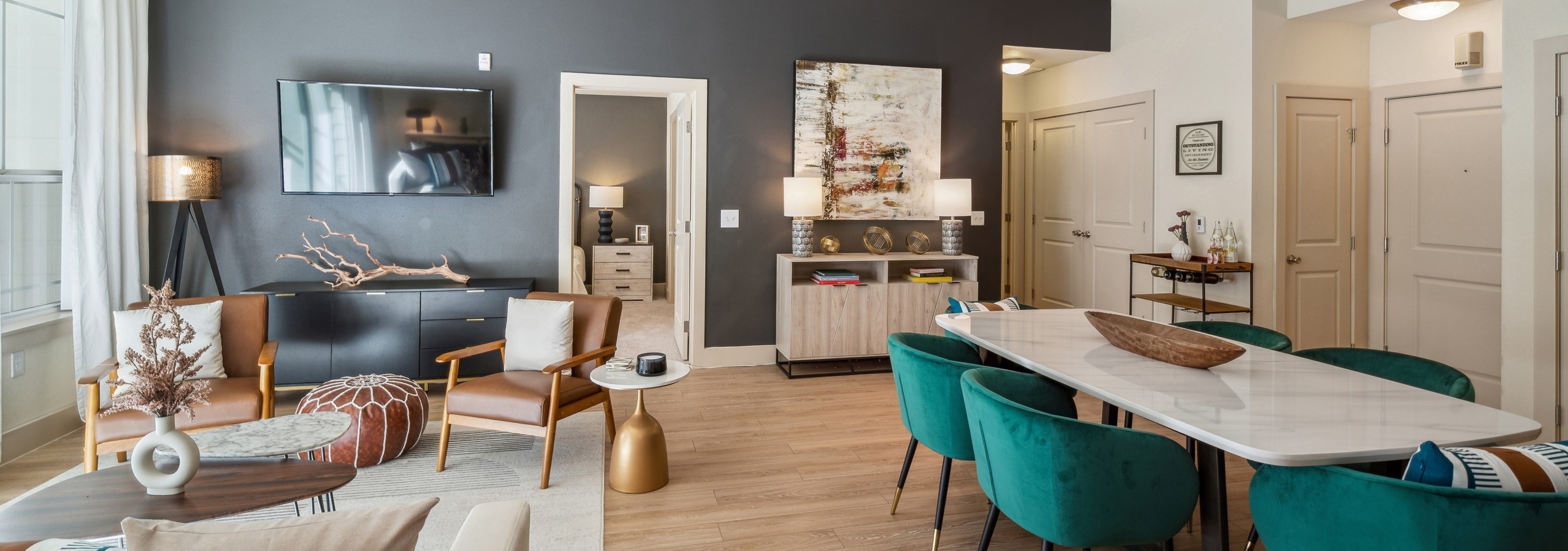 AMLI Park Avenue living and dining room with a white dining table and seating facing large TV set on wood floors
