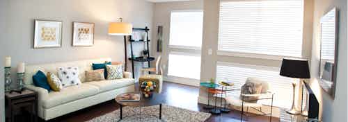 An interior view of a living room at AMLI Riverfront Park apartments with a couch and a large window and door to balcony