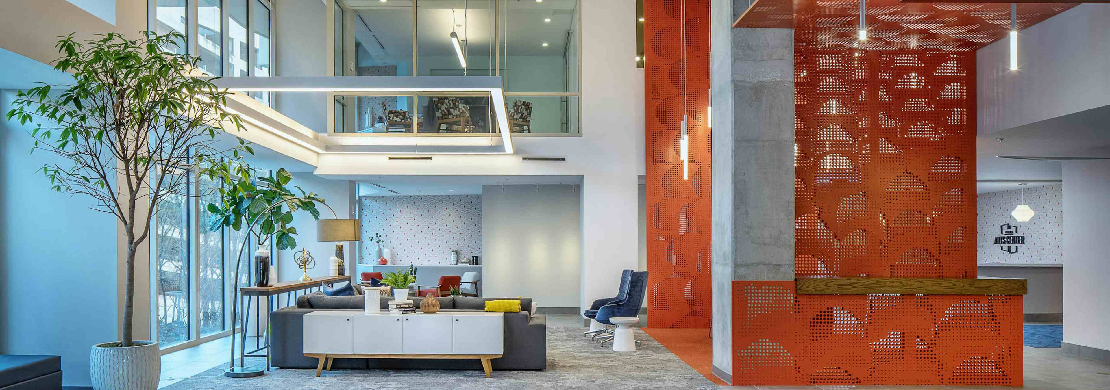 Interior of lobby at AMLI Arts Center with seating area and tall potted plants with modern light fixtures and raised ceilings