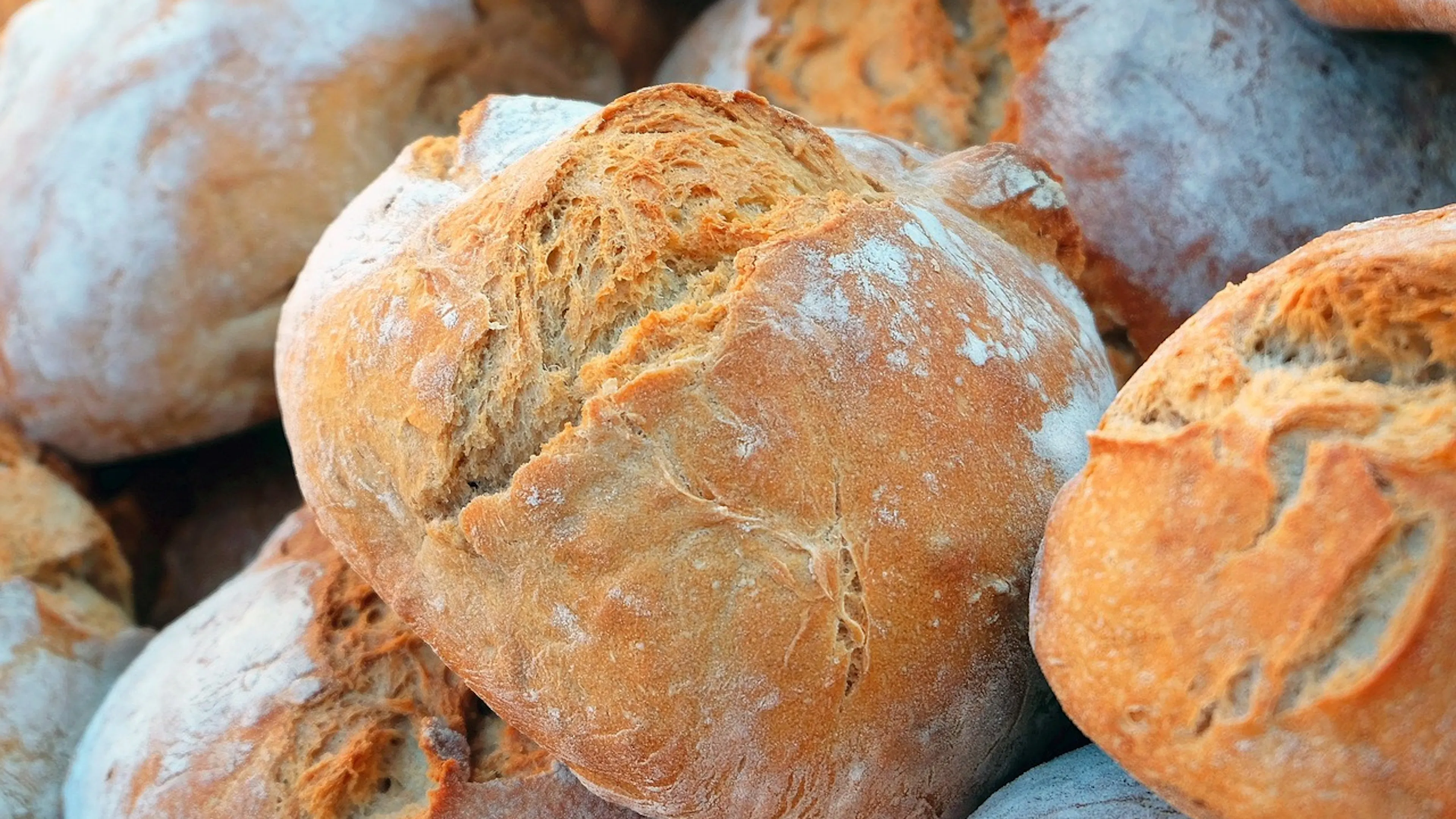Close-up of a round, crusty sourdough loaf resting on top of other loaves of bread