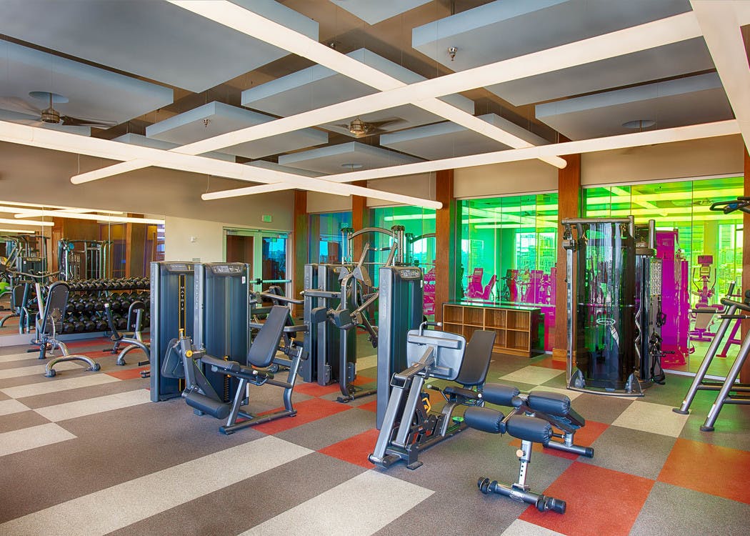 Fitness center at AMLI Denargo Market apartments with multiple strength training machines and free weights and large mirrors