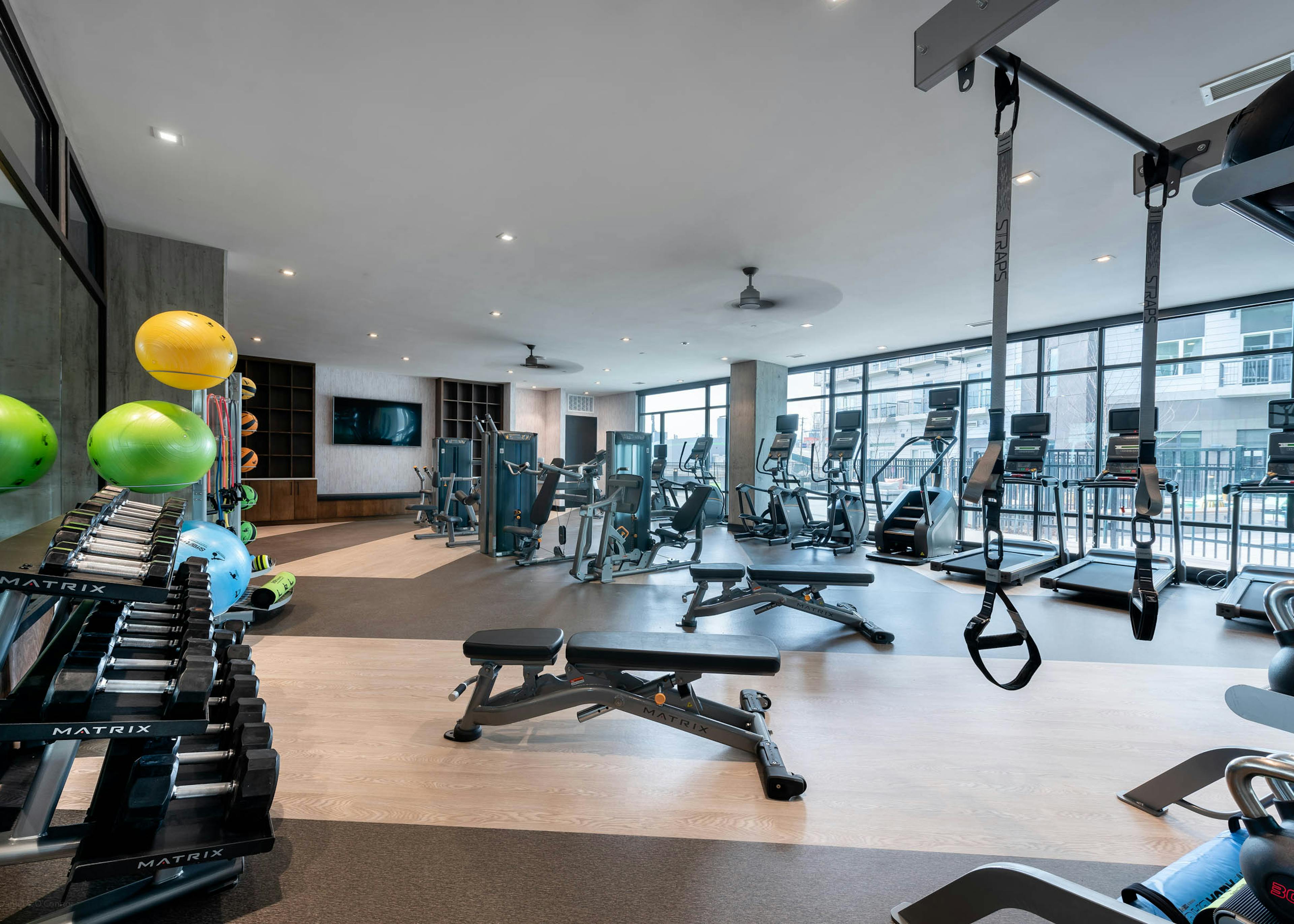 AMLI Art District fitness center with weights and cardio machines and a television and cabinets and floor to ceiling windows 