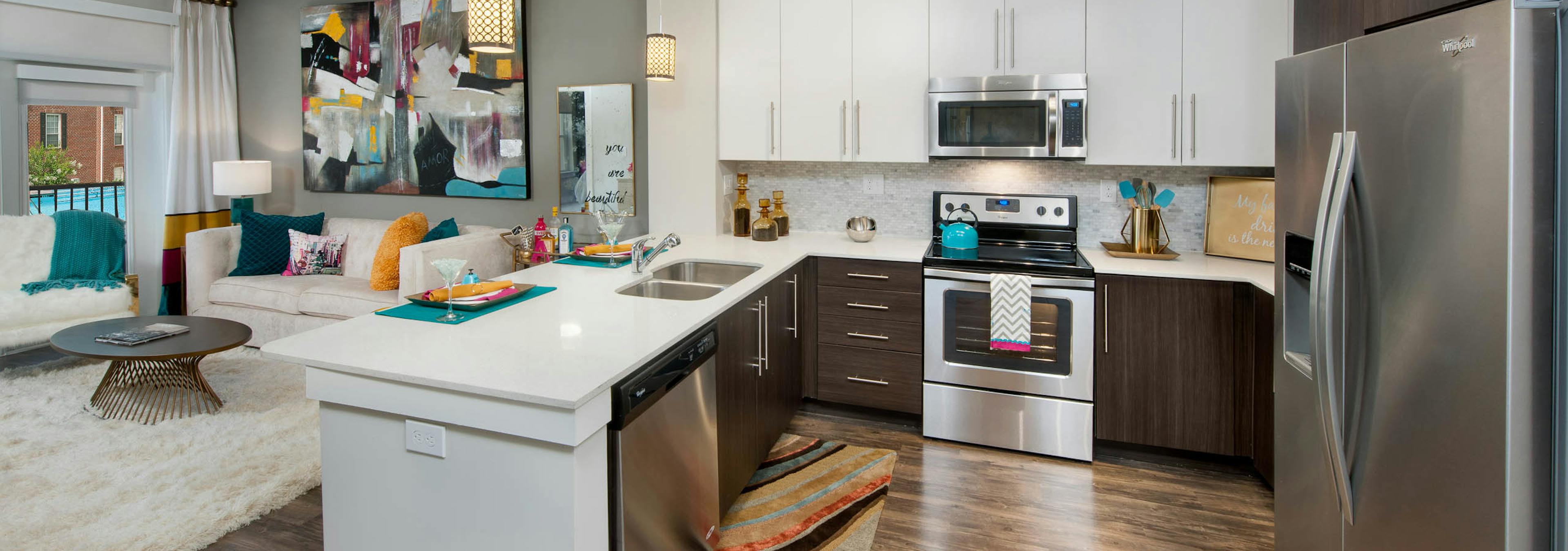 Interior of AMLI Piedmont Heights kitchen with stainless steel appliances and white granite countertops with dark hardwood