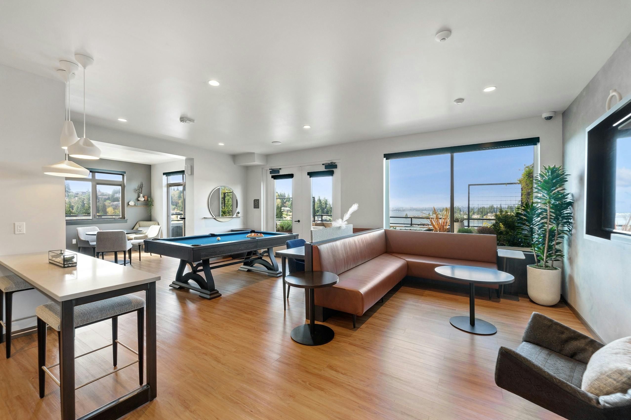 AMLI Bellevue Park sky lounge with brown leather couch and billiards table and large windows with view of Lake Washington