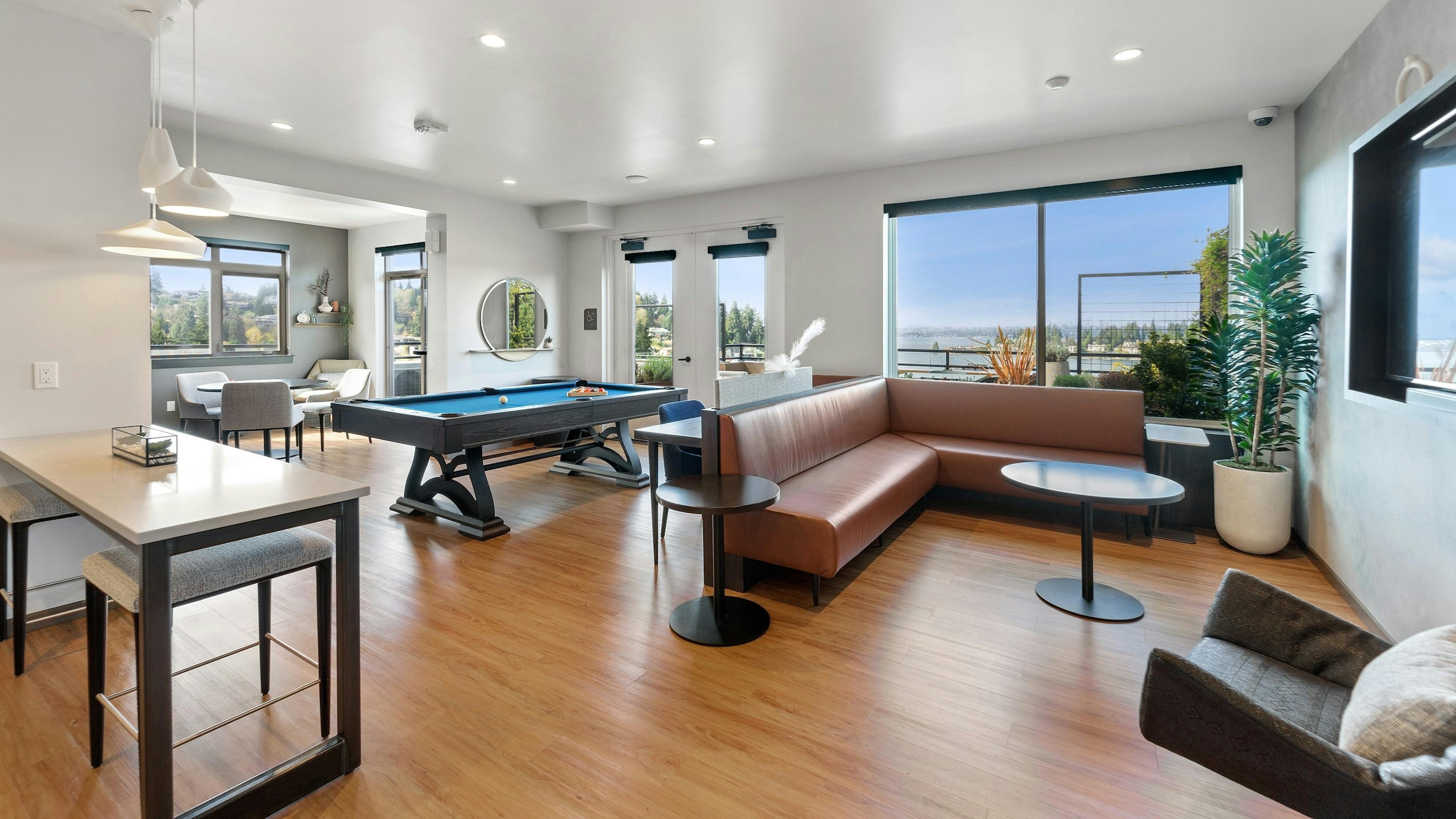 AMLI Bellevue Park sky lounge with brown leather couch and billiards table and large windows with view of Lake Washington 