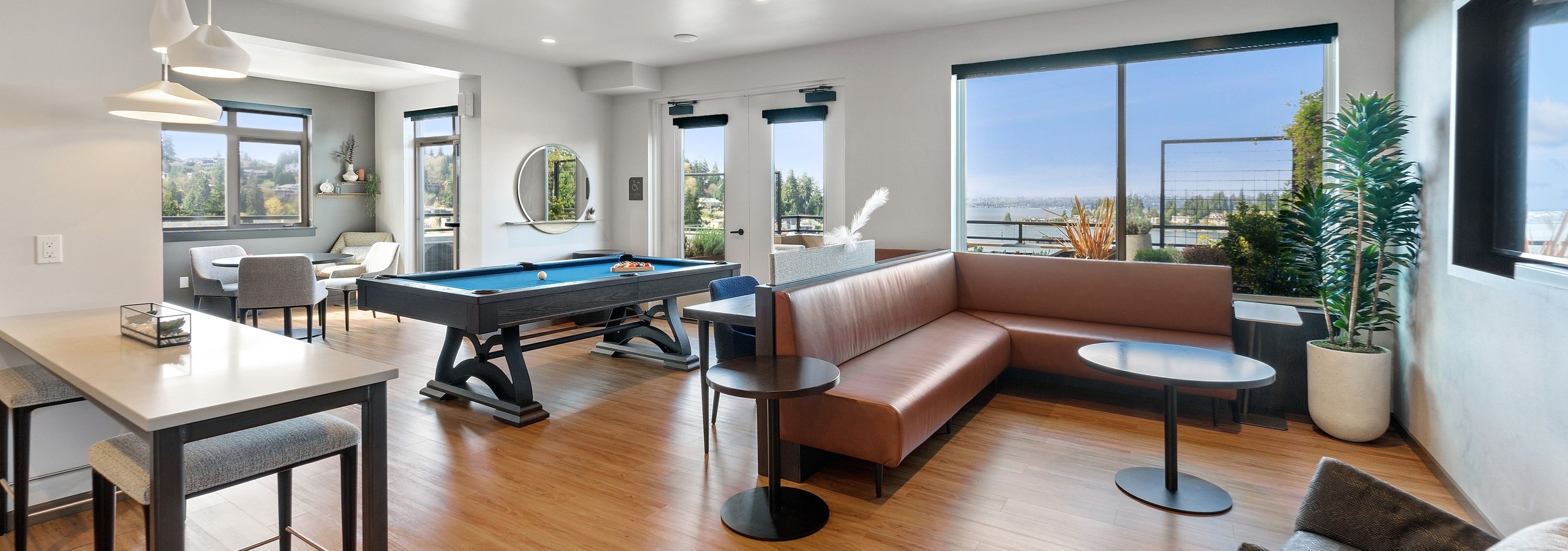 AMLI Bellevue Park sky lounge with brown leather couch and billiards table and large windows with view of Lake Washington