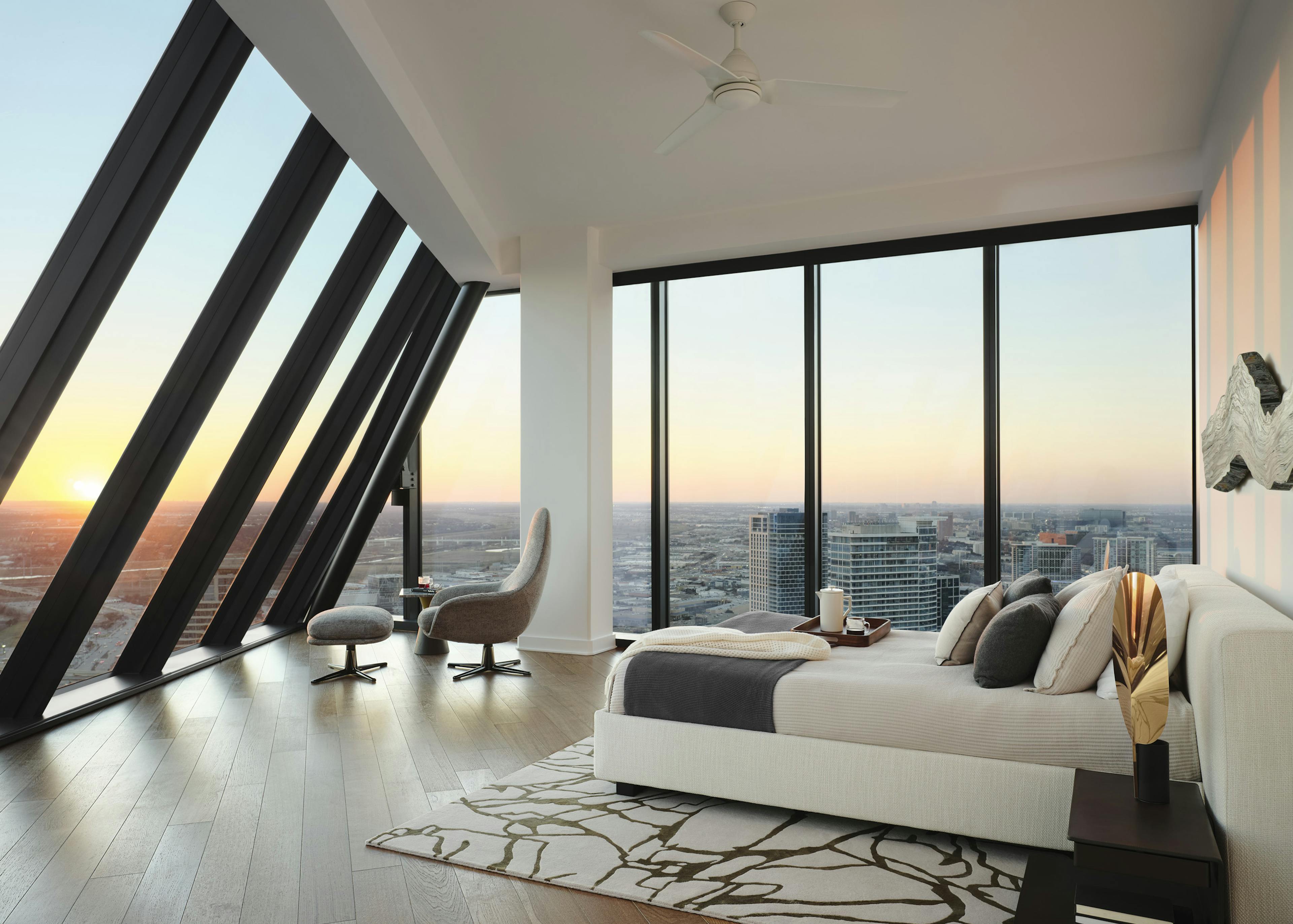 Interior view of AMLI Fountain Place apartment bedroom with two walls of floor-to-ceiling windows at sunset