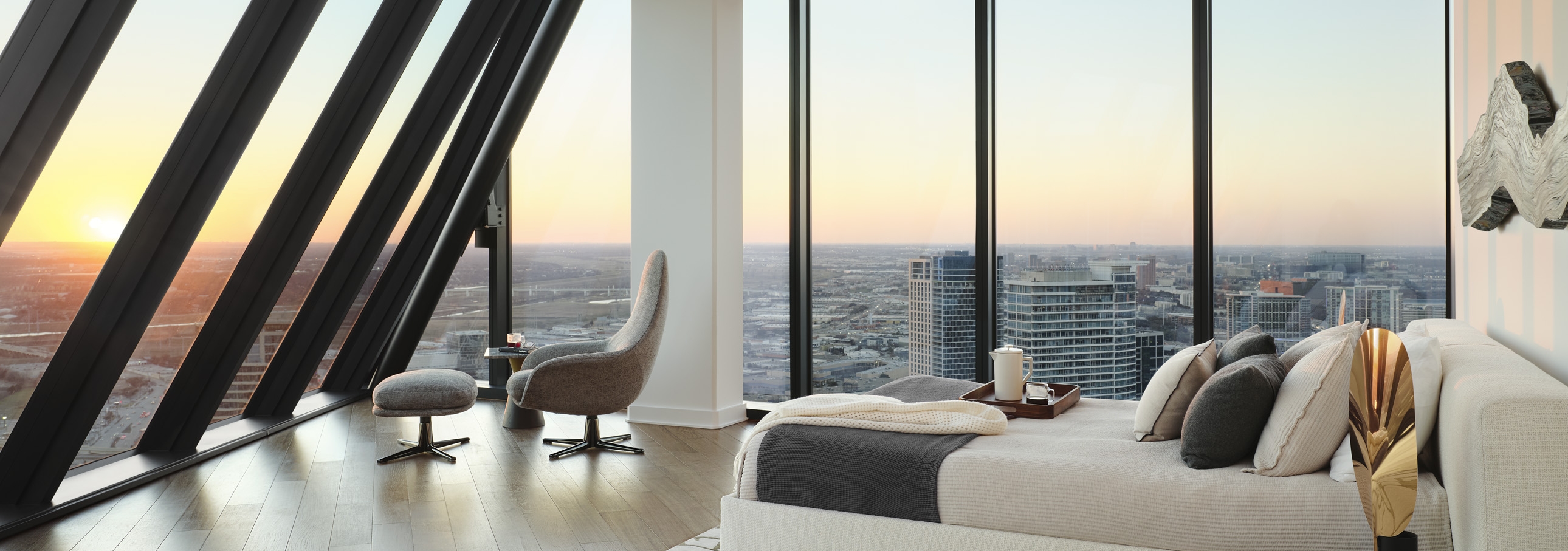 Interior view of AMLI Fountain Place apartment bedroom with two walls of floor-to-ceiling windows at sunset