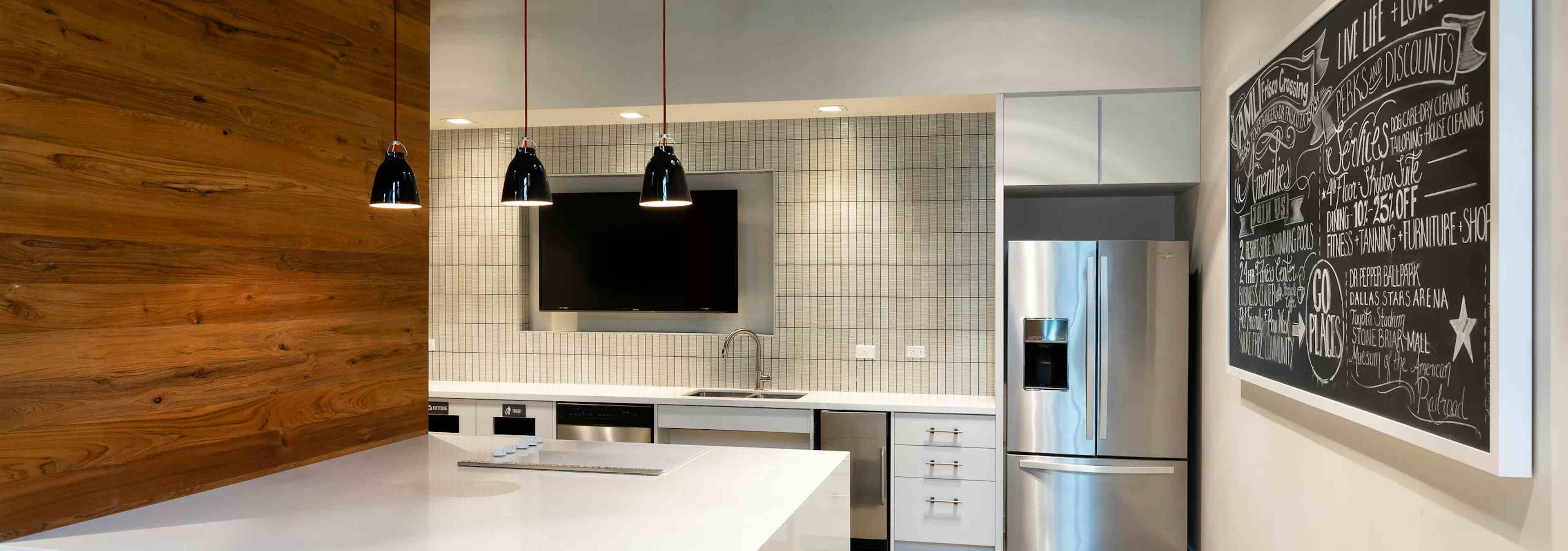 Interior of resident serving kitchen at AMLI Frisco Crossing apartment building with stainless steel appliances and big screen TV