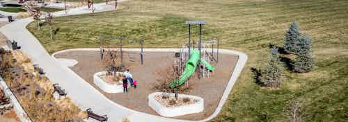 Daytime aerial view of a family at a children’s playground in park adjacent to AMLI Littleton Village apartment building