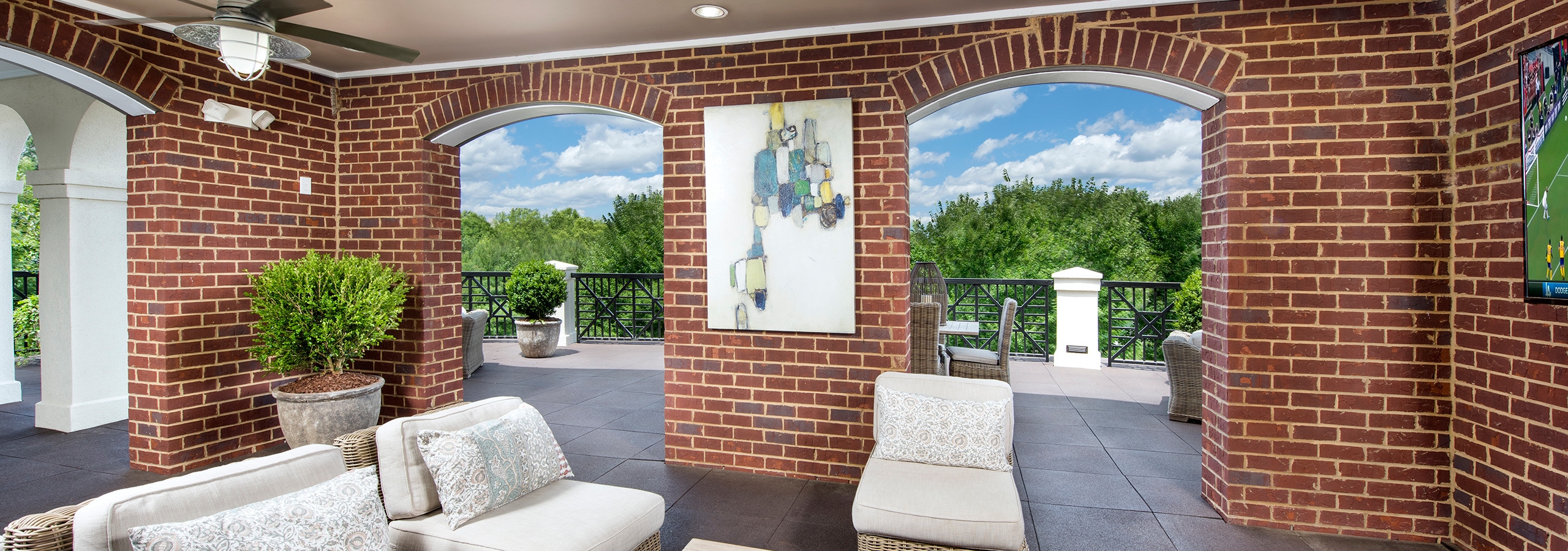 Master event room terrace at AMLI North Point with arched brick walls showing views of bright trees and a blue sky