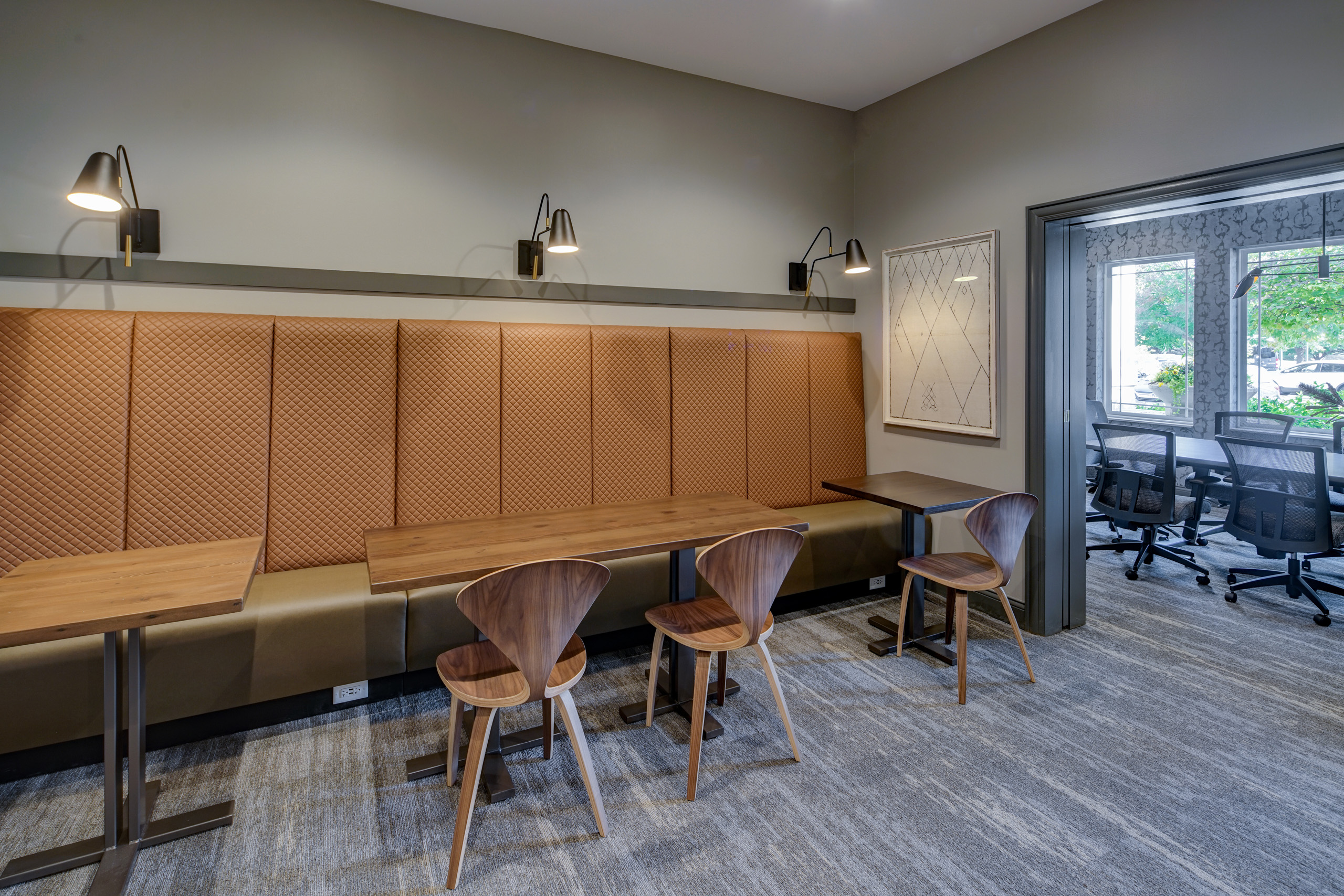 AMLI at Seven Bridges business center with beige banquette style seating and three tables and chairs along gray wall