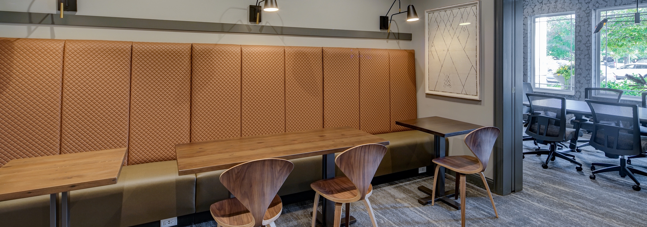 AMLI at Seven Bridges business center with beige banquette style seating and three tables and chairs along gray wall