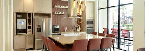 AMLI on Riverside resident kitchen with floor to ceiling windows and stainless steel appliances with big table for gathering